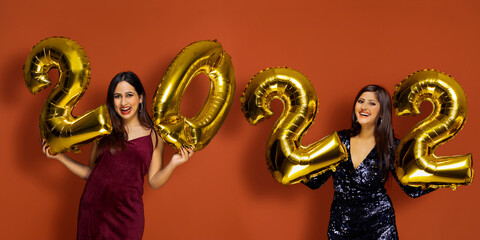 Young women holding 2022 golden balloons during a new year party