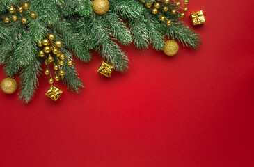Christmas composition. Coniferous branches and decorative ornaments on a red background.