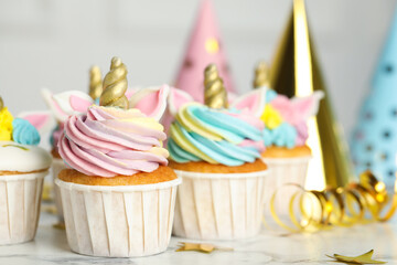 Cute sweet unicorn cupcakes and festive decor on white marble table, closeup