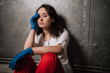 Obraz premium Nurse worker have headache migraine feel bad pain tired owerworked stressed touching temples. Female doctor dressed medical white gown blue sterile rubber gloves red pants, healthcare overwhelmed