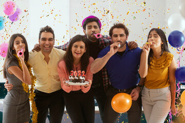 Colleagues celebrating new year together in office with balloons and cake. 	