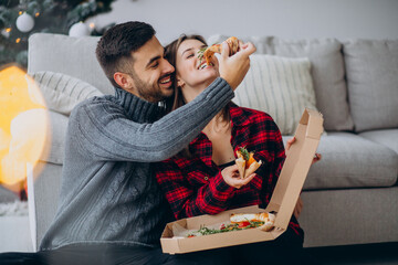 Young couple eating pizza at home on Christmas