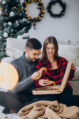 Young couple eating pizza at home on Christmas