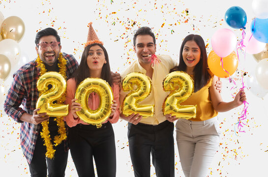 Friends celebrating new year holding 2022 balloons. 	