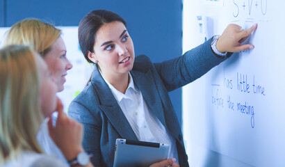 Business, education and office concept - business team with flip board in office discussing something.