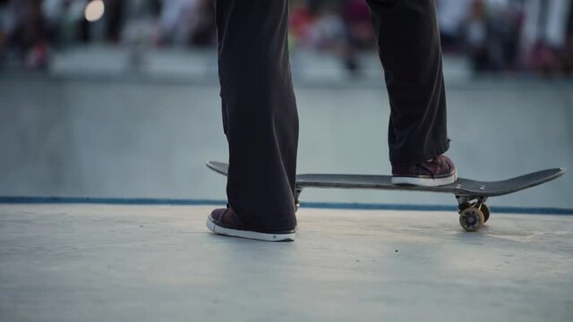 Skateboarder taking a rest in a skate park. The skater prepares to demonstrate the trick. Youth culture. A ramp for performing stunts.