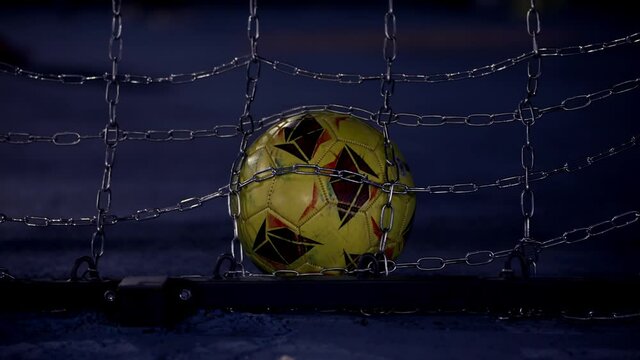 Soccer ball in the metal net. Football goal. Football goal in the twilight. Playground. Hit the target. Account opening.