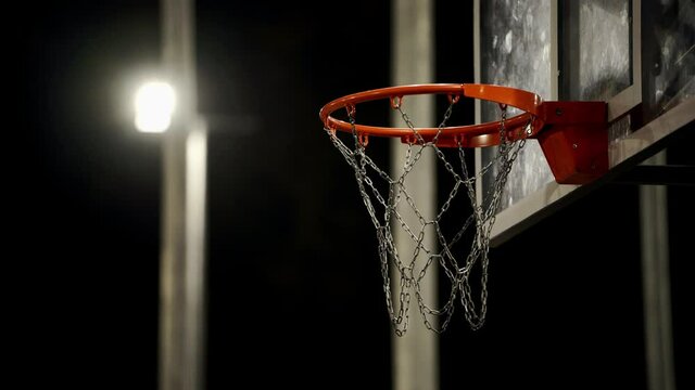 Lanterns illuminate the basketball court. Basketball hoop on a black background close-up. Basketball arena. A decisive moment in the game.