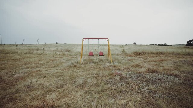  Swing in an abandoned place.  Swing without children. Abandoned playground. Extinction. Deserted territory.