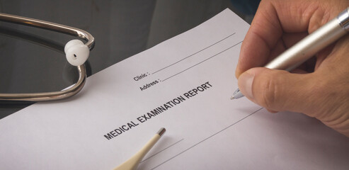 A medical examination report on the table. Hand writing a medical examination report.