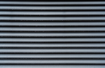 Corrugated metal sheet fence with water drops. Modern metal profile fence with shutters or blinds...