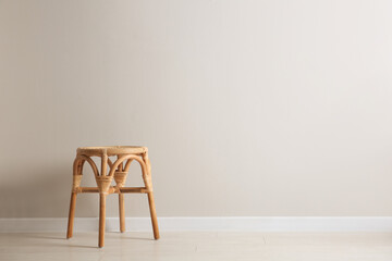 Fototapeta premium Stylish wooden stool near white wall, space for text. Interior element