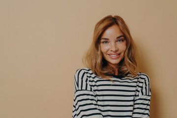 Fototapeta premium Portrait of lovely woman with minimal natural makeup smiles gently looks directly at camera