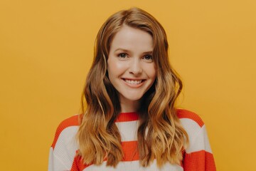 Happy teen girl sending positive energy to someone while standing isolated over yellow background