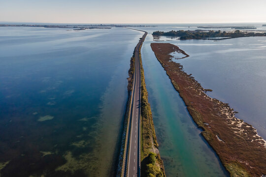 Aerial view of vehicles driving on a beautiful road crossing the lagoon in Grado near Gorizia, Friuli Venezia Giulia, Italy.