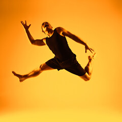 Fototapeta na wymiar Gymnastic young man jumping all orange
