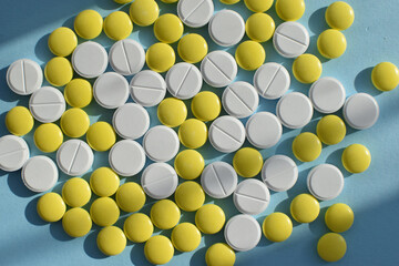 Antiviral white and yellow tablets for treatment on a blue background. Flat lay, top view