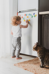 little cute toddler playing with toy letters on the fridge