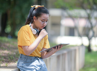 A teenage woman looks down at the tablet in her hand with a worried expression.