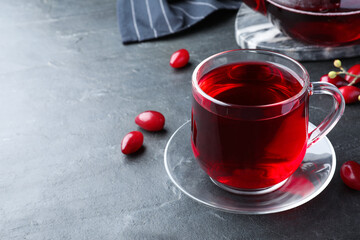 Glass cup of fresh dogwood tea and berries on black table. Space for text