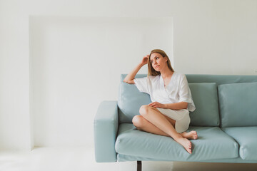 portrait of a young charming woman in a silk robe at home on the sofa