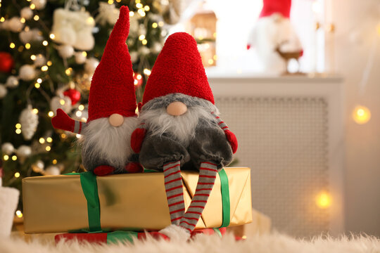 Cute Christmas gnomes and gift boxes on carpet in room
