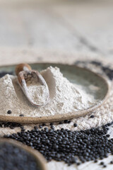 Plate with black lentils flour and beans with a wooden scoop close up