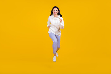 Fototapeta na wymiar Photo of charming energetic lady jump run forward wear white hoodie isolated yellow color background