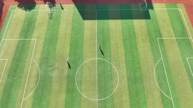 Drone aerial view of student playing football in football field Shanghai China, sports education and training exercise concept b-roll footage. Player kick pass the ball to each other cozy sunny day