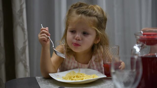little girl eats pasta at lunch. The child choked on pasta and regurgitates them back into the plate