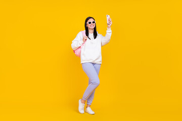 Fototapeta na wymiar Full size photo of lady blogger hold rucksack make selfie video record smart phone isolated over bright yellow color background