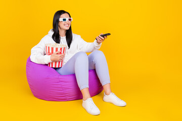Full body photo of positive lady sit bag chair watch comedy hold pop corn basket isolated over shine color background - obrazy, fototapety, plakaty
