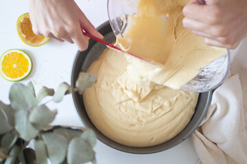Food ingredients on white background. Cooking flat lay, top view. Young woman baking an orange cake. Homemade concept.
