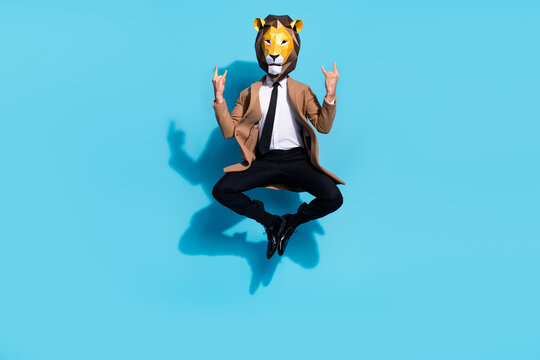 Full body photo of weird anonym guy lion mask jump up show horned symbol isolated over blue color background