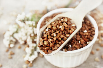 Wooden spoon of roasted buckwheat and groat jar, gluten free ancient grain for healthy diet,...