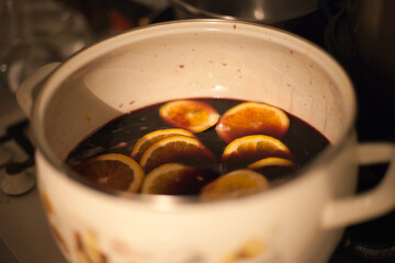 Making mulled wine - putting sliced oranges in a pot with red wine. Homemade mulled wine preparation.