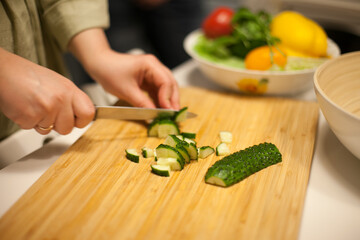 woman cutting cucumbers preparing a salad 