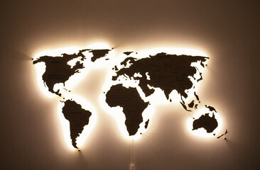 Fototapeta na wymiar map of the world on the wall glowing with soft cozy light. Map as a home decor and lighting.