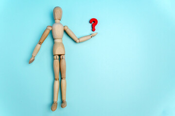 Wooden figurine of a man with question mark on a blue background with space for text. Flat lay