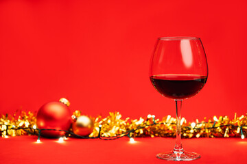 Glass of wine with christmas decoration on red background christmas drink concept