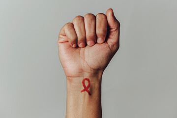 red ribbon for the fight against AIDS in his wrist - obrazy, fototapety, plakaty