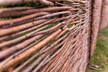 Fence made of wooden rods. Wicker fence made of twigs. Background, texture, garden decor element