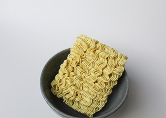 Square instant noodles before cooked, inside grey bowl, isolated on white background
