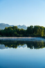 Fototapeta premium Just after sunrise on a summer day, the Teton mountains reflect on a lake with crystal clear water