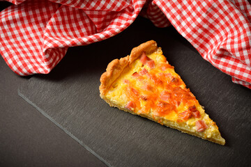 Slice of traditional French pie quiche Lorraine with ham, onion and eggs. Backed custard dough...