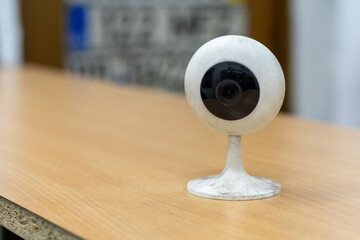 Photo of a white round surveillance camera on a wooden table