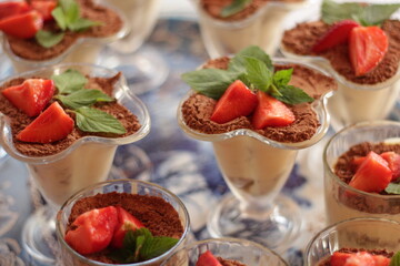 Strawberry tiramisu in a glass decorated with mint leaves and strawberry slices . Classic Italian dessert . Blue background