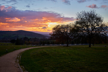 Naklejka na ściany i meble Sunset in a park. Sunset in autumn, view of a park with the mountains in the background