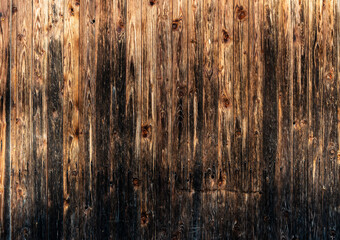 A weathered gray and brown wall made of wooden slats