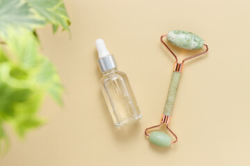 Fototapeta na wymiar Hyaluronic acid or serum bottle with jade massage roller and plant branch. Face massage, lifting and toning treatment, top view, flat lay